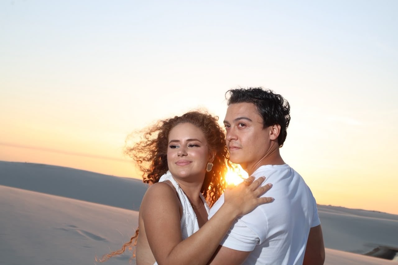 Casal abraçado ao pôr do sol nas dunas