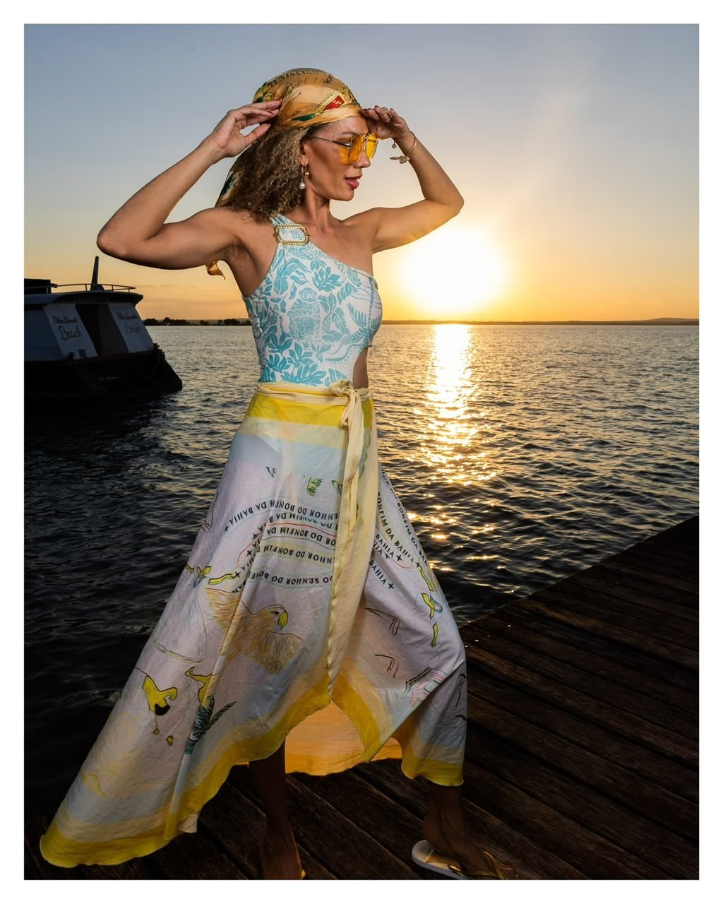 Mulher com vestido estampado em píer ao pôr do sol